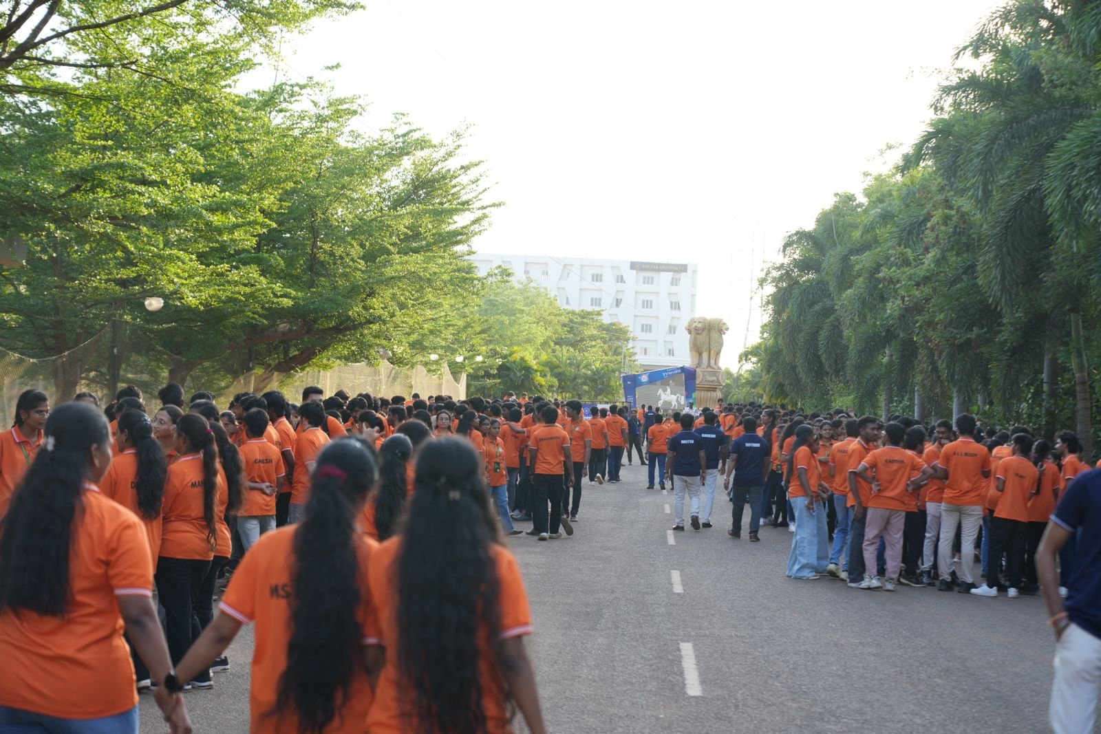 Students processing down the tree-lined avenue toward the main stage